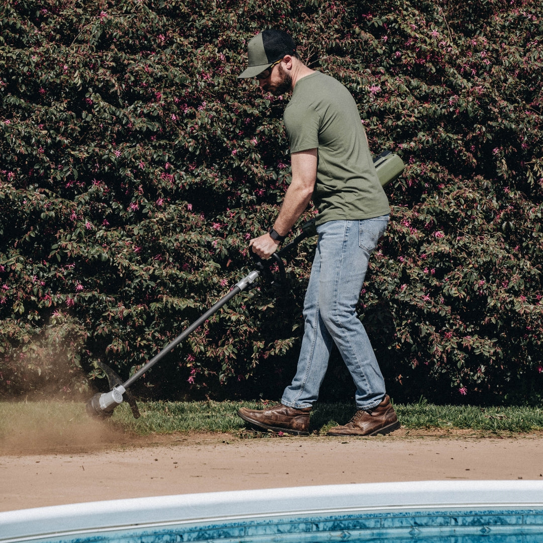 Man using Green Machine string trimmer to edge the lawn.
