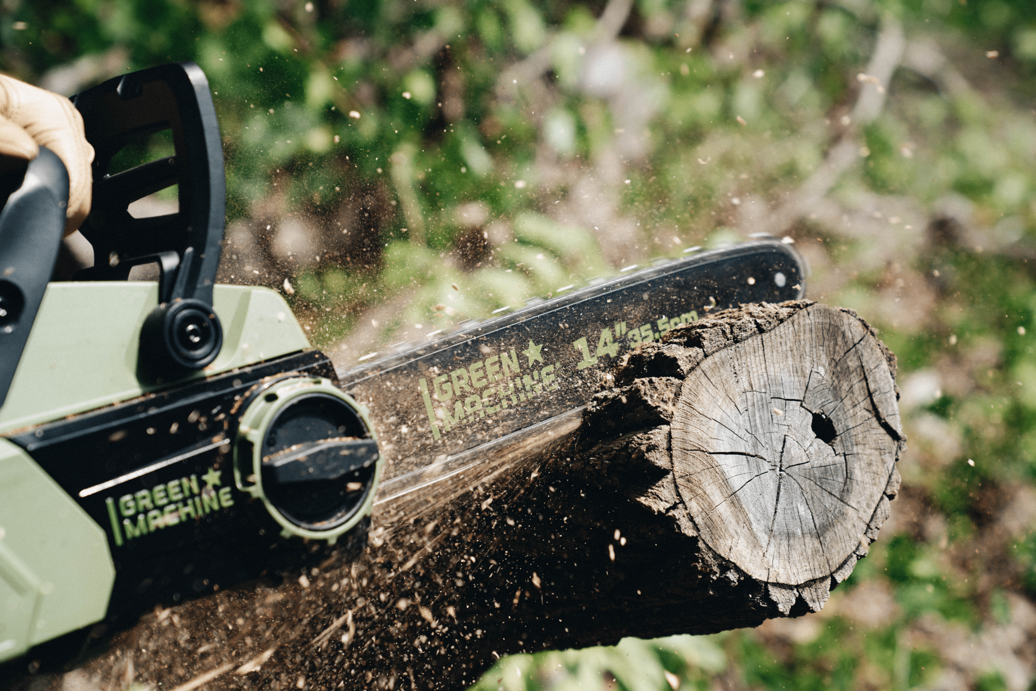 Green Machine 14 inch chainsaw cutting through tree branch.