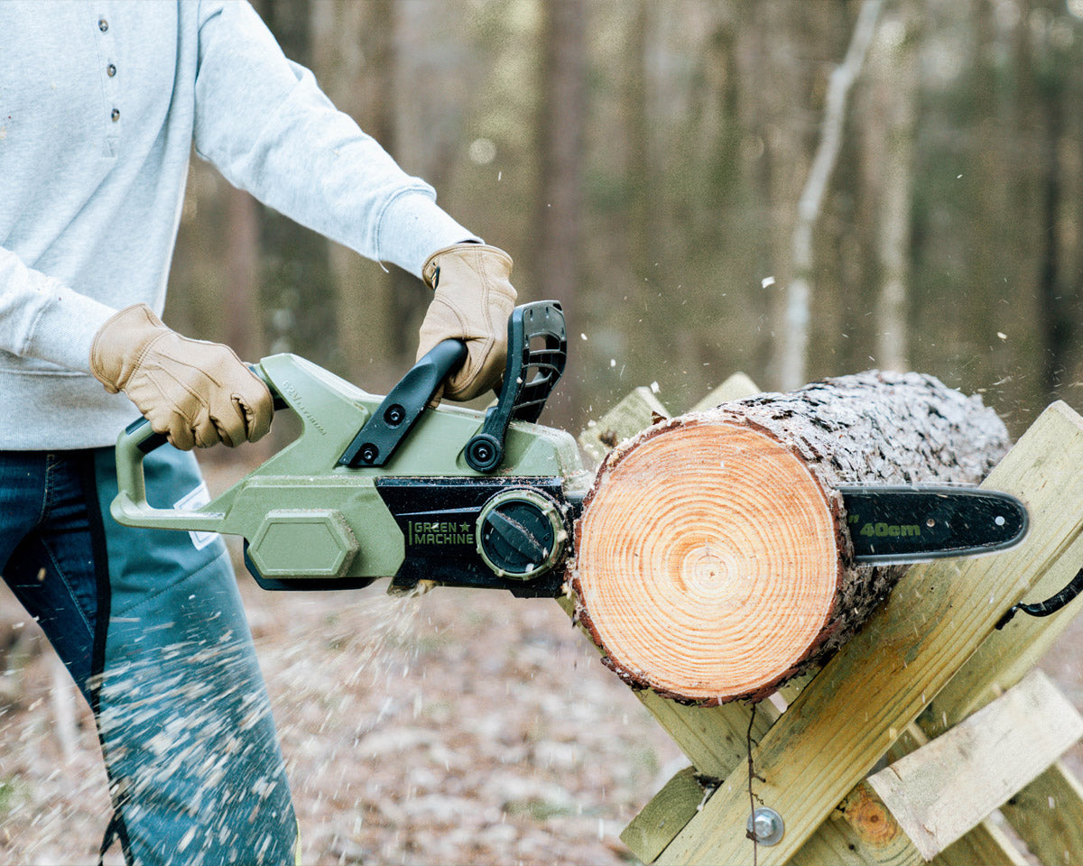 Person cutting tree trunk with Green Machine chainsaw.