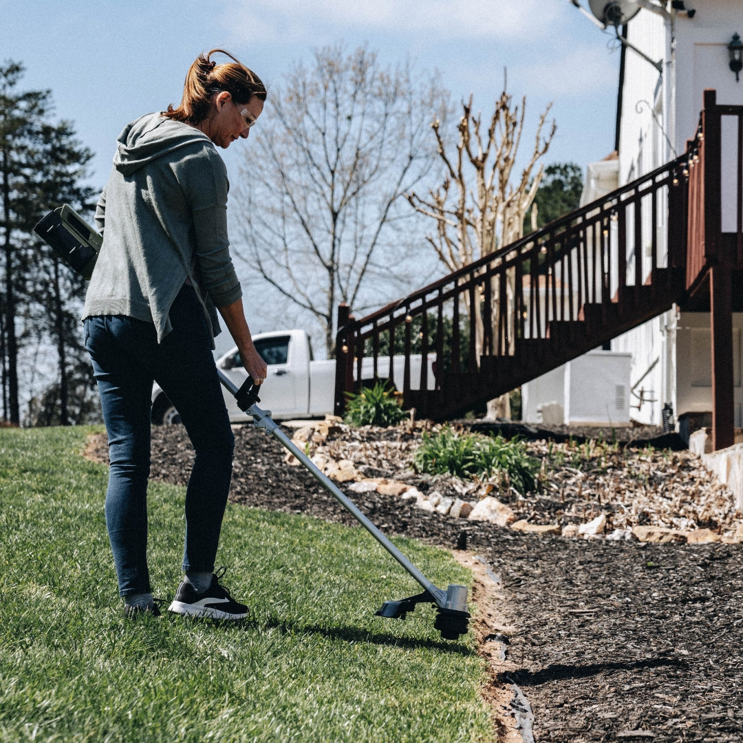 Woman using Green Machine string trimmer to edge the lawn.